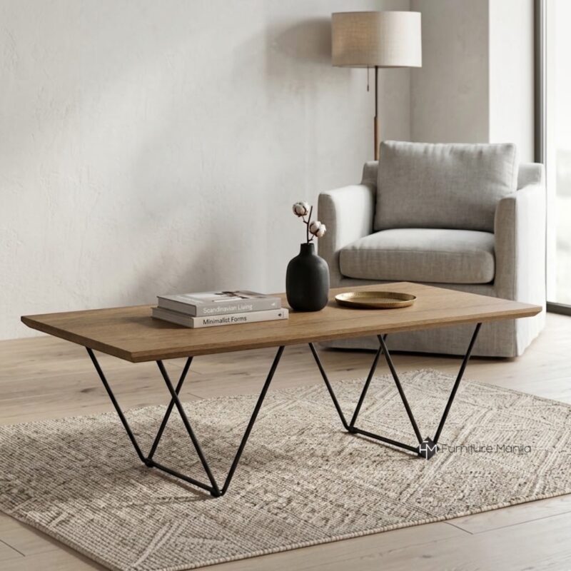 A modern light wood coffee table with geometric wireframe legs, set in a styled neutral living room corner.